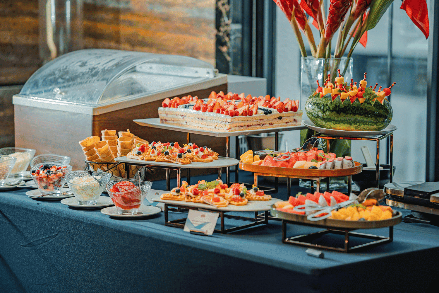 Buffet table with various desserts, fruit platters, and pastries in a banquet setting.