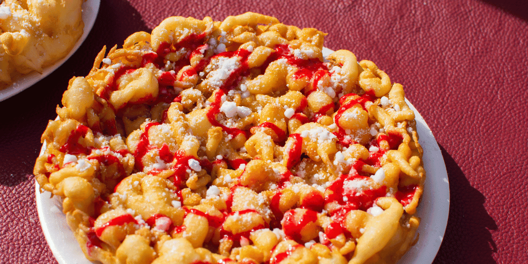 Funnel cake with powdered sugar and red syrup drizzle on a white plate.