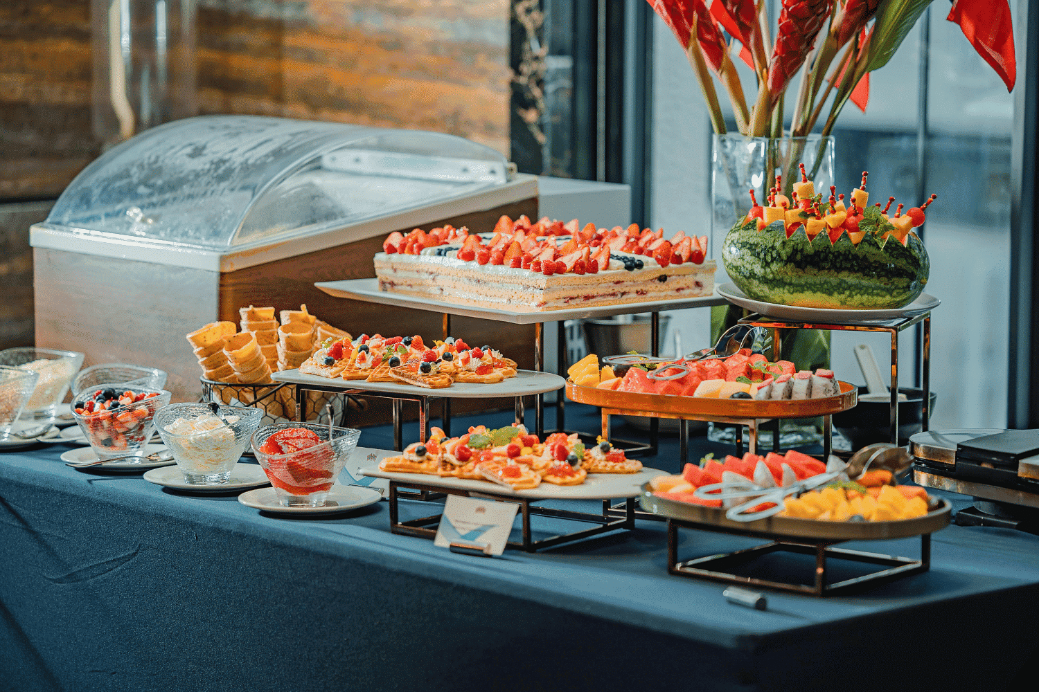 Buffet table with various desserts, fruit platters, and pastries in a banquet setting.