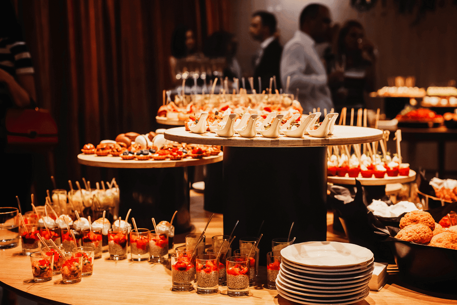 Buffet table with assorted appetizers, including skewers, hors d'oeuvres, and colorful desserts.